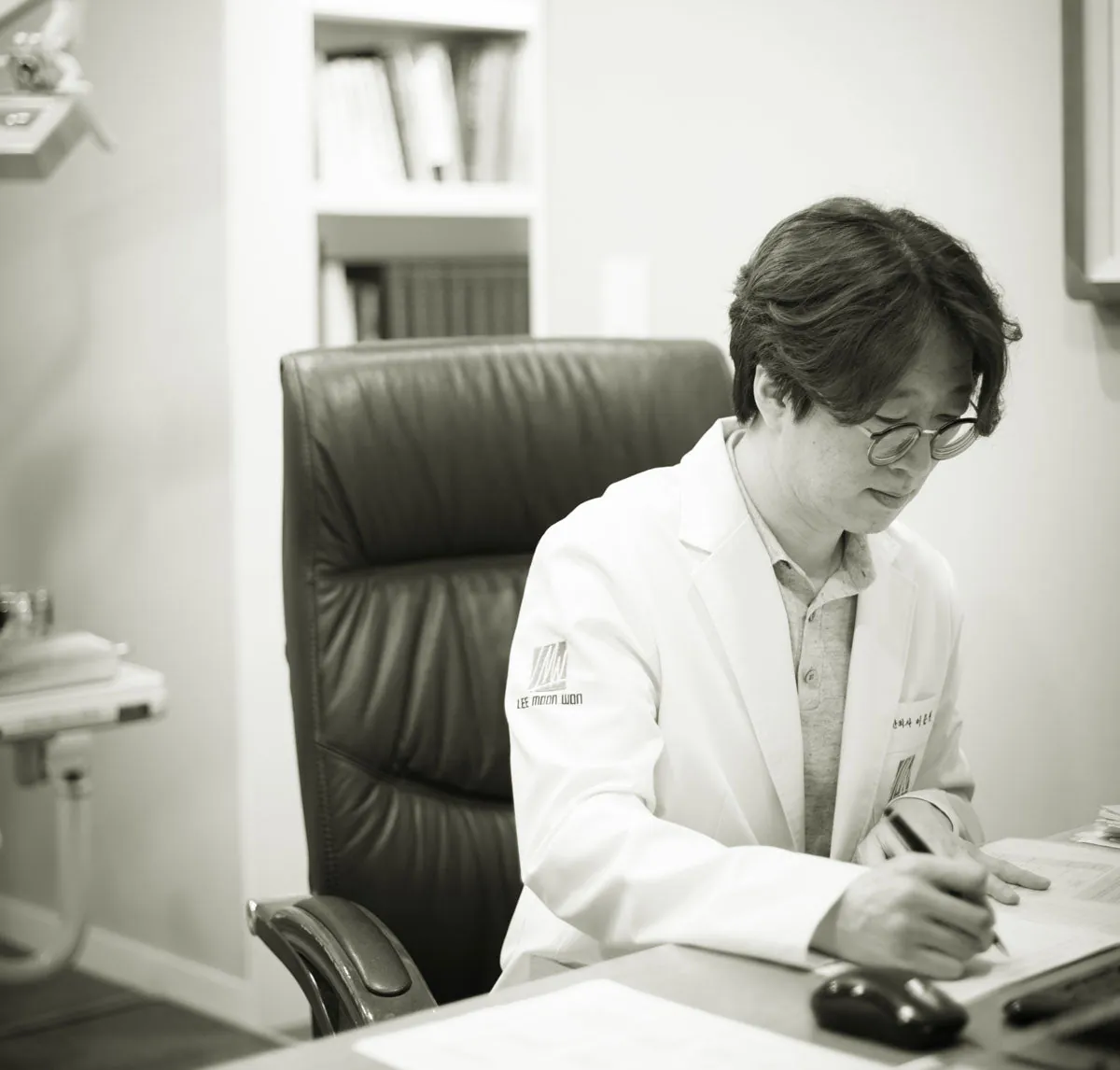 책상에서 글을 적는 이문원 대표원장 흑백 사진